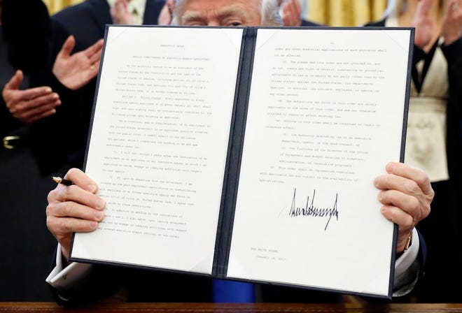 President Donald Trump holds up a signed Executive Order in the Oval Office of the White House, Saturday in Washington. (AP Photo/Alex Brandon)