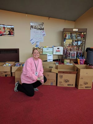 Physical Education/ Health coordinator Michele Sharpe squats near boxes of items donated by the Fall River School Department.