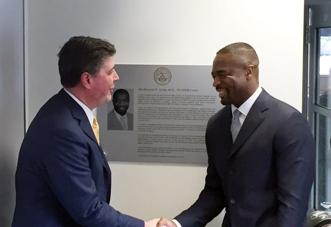 Worcester State University President Barry Maloney congratulates Dr. Imoigele Aisiku after unveiling the plaque in the background recognizing Dr. Aisiku inside WSU's Ghosh Center for Science and Technology. T&G Staff/Scott O'Connell