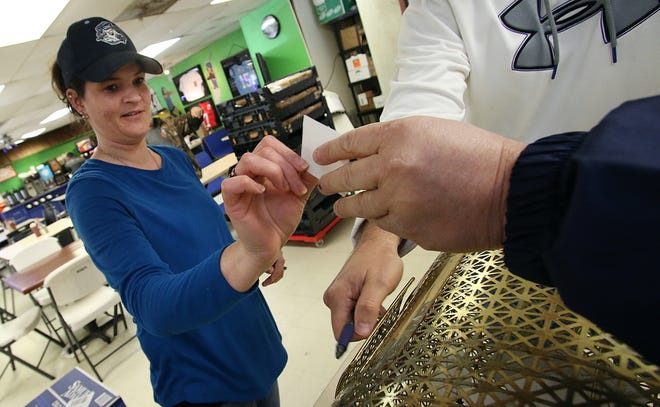 Erica Walker draws and hands the first raffle ticket to Tug Deason as Brent Grice closes the raffle ticket drum Tuesday morning at Timeout C Store. The drawing was the first in the" 30 Guns in 30 Days" raffle to raise money for Stanley's new gym. PHOTO MIKE HENSDILL/THE GAZETTE