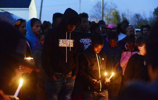 Isaiah Hicks, left, and his siblings gathered with family and friends at a prayer vigil Tuesday for their father Alton McKnight on Tiffany Street. McKnght died from multiple gunshot wounds Monday evening.