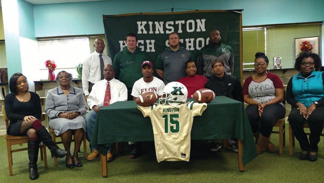 Jarquez Bizzell, center wearing hat, announced his decision to sign with Elon University on Wednesday at Kinston High School. Accompanying Bizzell are, seated from left, girlfriend Trinity Hines, grandmother Edna Bizzell, father Linwood Lee Bizzell Jr., mother Jackie Rouse, brother Cortez Hill, cousin Bria Myers and aunt Selena Moore. Standing, from left, are Kinston principal Brian Corey, running backs coach Ryan Buie, football coach Ryan Gieselman and defensive coordinator Corey Bryant.