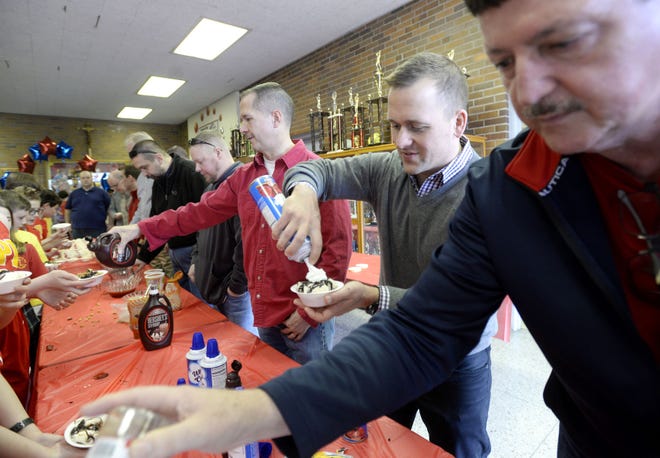 Fathers and grandfathers of students serve ice cream sundaes Thursday as part of Catholic Schools Week at SS. Peter and Paul School in Beaver. From right are Howard Stuber, Nate Goshen and Kris Faulkner.
