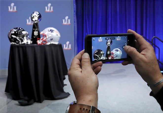 An attendee snaps a photo of the Vince Lombardi Trophy and team helmets during NFL Commissioner Roger Goodell's press conference at Super Bowl 51, Wednesday in Houston.