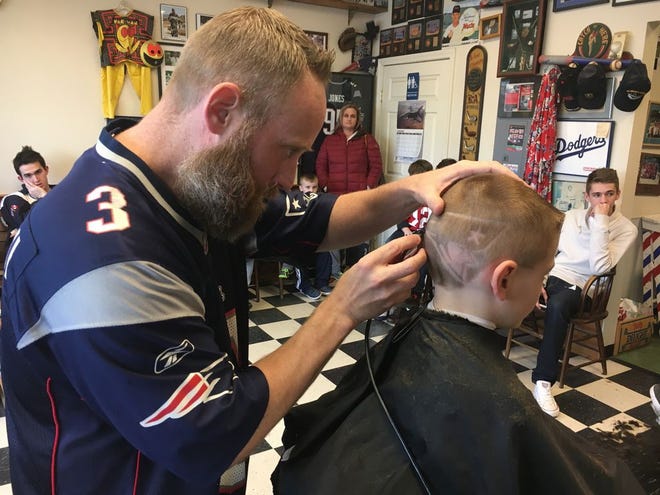 Darren Shea cuts a Patriots logo into the hair of Cameron Howell, 6, of Halifax.