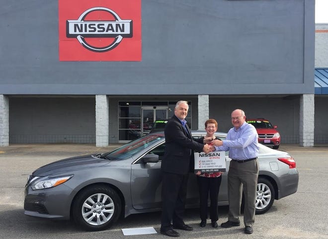 Nissan of Shelby general manager Scott Wade hands off the keys of a 2016 Nissan Altima to John and Lorraine Royster. The couple won the car through a scratch off mailer. Casey White/The Star
