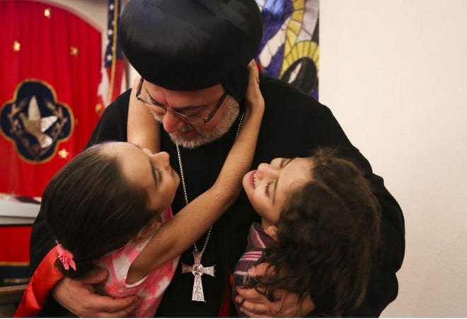 Archbishop Dionysius John Kawak hugs Gabriella Kouki, 8, left, and Marie Shabo, 7, after the three-hour service. It was attended by more than 200 Orthodox Christians, who are a minority in their Syrian homeland. [ EVE EDELHEIT/TAMPA BAY TIMES ]