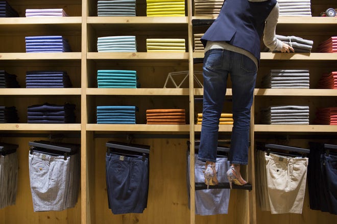 An employee on a ladder arranges shirts at J. Crew Group's new men's store in the Central district of Hong Kong, China, on May 22, 2014. Brent Lewin/Bloomberg