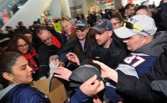 New England Patriots Pro Shop employee Maribel Tejada, left, hands out Super Bowl LI locker room caps to customers at Gillette Stadium in Foxborough, Mass., Monday, Feb. 6, 2017, a day after the Patriots defeated the Atlanta Falcons in Super Bowl LI.