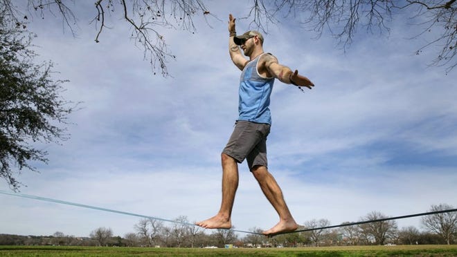 On a spectacularly warm and sunny winter day in Austin Jordan Turnage works on his new hobby, slack lining, in the Great Lawn of Zilker Park on Tuesday afternoon. The record warm temperatures in Central Texas are also bringing wildfire risk, according to weather and fire officials.