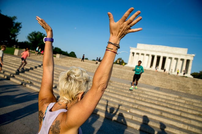 A member of the running group November Project cheers on a friend as she finishes running up and down the stairs of the Lincoln Memorial in Washington, D.C. [ANDREW HARNICK / AP]