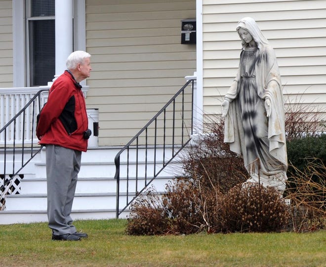 Head usher Mickey Gillis of Saint Edith Stein Church inspects the damage done to the statue of Mary, which is one of four that was vandalized outside Saint Edith Stein Church in Brockton.