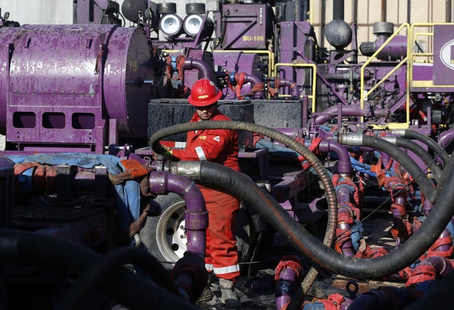 In this March 25, 2014 file photo, a worker adjusts hoses during a hydraulic fracturing operation at a gas well, near Mead, Colo. (AP Photo/Brennan Linsley, File)