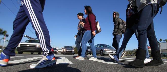Embry-Riddle Aeronautical University students cross Clyde Morris Boulevard in the crosswalk, on their way to classes, recently as three lanes of traffic wait patiently at the traffic light. [News-Journal/David Tucker]