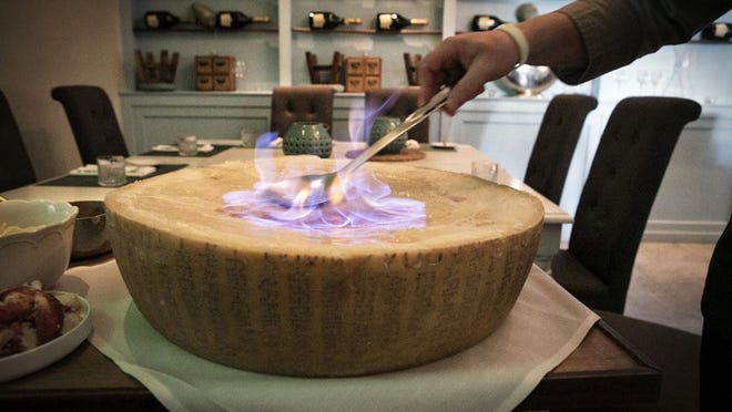 Chef Laurent Godbout of Chez L’Epicier flambés cognac atop a giant Italian parmesan cheese wheel that has been aged for 36 month. This Valentines Day Godbout will melt the cheese table side and incorporate pasta, lobster, chives, and bisque to create a special romantic experience for diners. Damon Higgins / Daily News