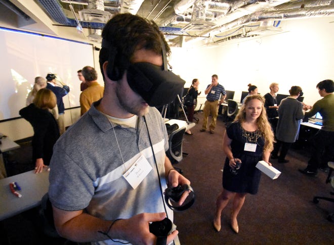 Brock Wilkinson of North Port tries a virtual reality game as his wife, Meredith, watches Thursday evening at Ringling College of Art & Design. [Herald-Tribune photo / Carla Varisco]