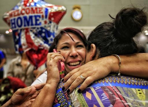 Cuban health worker Veidy Diaz, center, is greeted Monday by family and friends as she talks on the phone after finally leaving the immigration and customs section of Miami International Airport. She was part of the group of Cuban health workers that traveled from Colombia after being allowed entry to the United States.