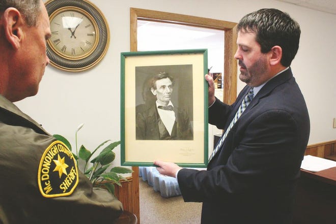 McDonough County State’s Attorney Matt Kwacala, right, holds a framed photo of Abraham Lincoln that was discovered in the courthouse’s shred room while the state’s attorney’s office was undergoing renovation. At left is Sheriff Rick VanBrooker. The print is framed with a matte bearing the seal of former Illinois Secretary of State Charles F. Carpenter. Carpenter sent a print to every county in the state in 1955 with the instruction it be displayed in each county’s courthouse.