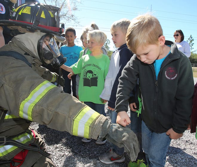 University Academy kindergartner Luke Peaden, 6, tests the toughness of firefighter Josh Crane's suit during a tour of the Bay County Emergency Operations Center in Southport on Friday. [ANDREW WARDLOW/THE NEWS HERALD]