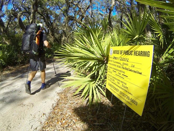 David DeLong of Tampa hikes past a sign on Cumberland Island announcing a Feb. 7 public hearing about a plan to develop 87.5 acres adjacent to this stretch of the Main Road.