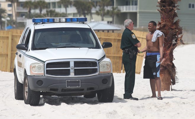 An officer speaks with a beachgoer March 16, 2016, at Club LaVela. [PATTI BLAKE/THE NEWS HERALD]