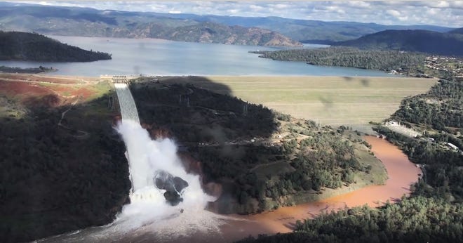 This Feb. 10 image from video provided by the office of Assemblyman Brian Dahle shows water flowing over an emergency spillway of the Oroville Dam in Oroville, Calif., during a helicopter tour by the Butte County Sheriff's office. [JOSH F.W. COOK/OFFICE OF ASSEMBLYMAN VIA A.P.]