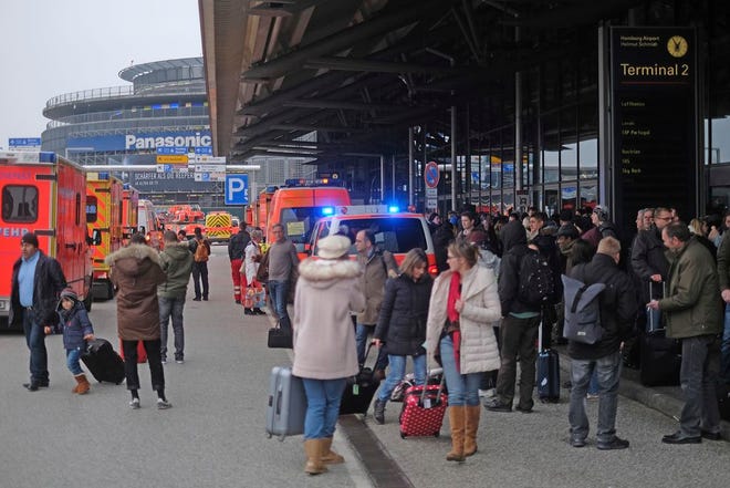 Travellers wait outside the Hamburg, northern Germany, airport Sunday, after several people were injured by an unknown toxic that likely spread through the airport's air conditioning system. (Axel Heimken/dpa via AP)