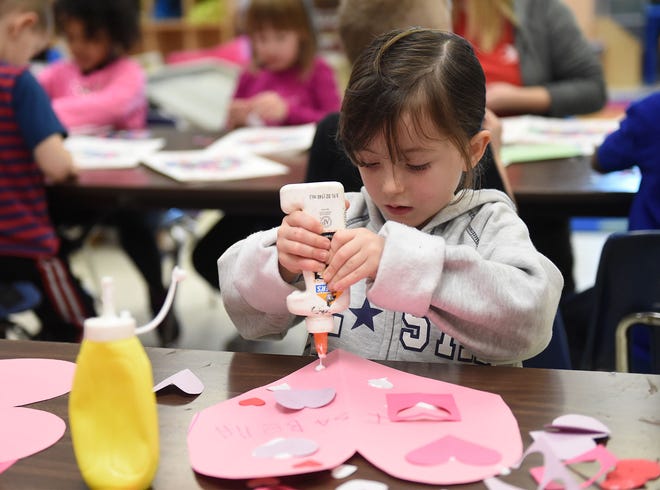 Isabella Hayes, 4, puts down glue to add hearts to a Valentine's Day card for family at the Lower Bucks Family YMCA on Wednesday, Feb. 8, 2017.