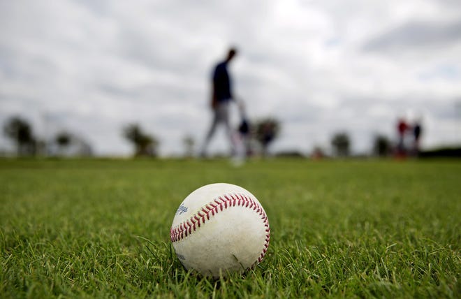 A baseball sits on the field as Red Sox players work out during spring training in Fort Myers on Monday. The Orioles, Pirates and Rays all begin spring training workouts in the area today. [THE ASSOCIATED PRESS / DAVID GOLDMAN]