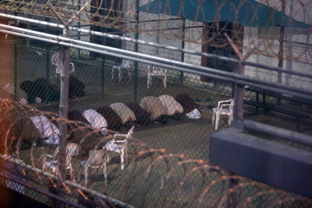 War-on-terror captives from two different cellblocks, separated by a fence, conduct communal evening prayers at the Camp 6 prison building for cooperative captives at the U.S. Navy Base at Guantanamo Bay, Cuba, on Tuesday, July 7, 2015. This photo was taken through a closed window. U.S. Army soldiers reviewed this photo invoking Pentagon security restrictions and cleared it for release. (Walter Michot / Miami Herald / TNS)
