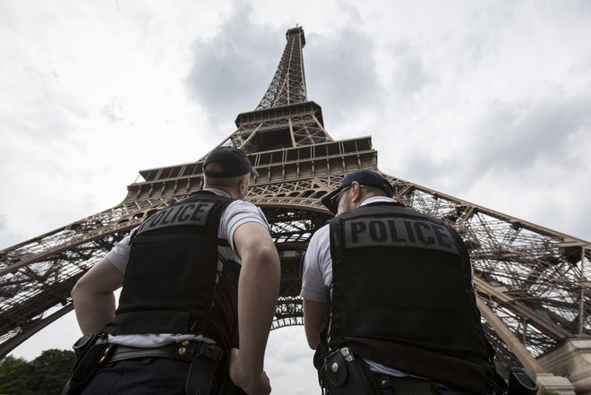 In this Friday, June 10, 2016 file photo, French riot police officers patrol under the Eiffel Tower. Paris authorities say Thursday, Feb. 9, 2017, they are proposing to replace the metal security fencing around the Eiffel Tower with a more aesthetic glass wall. THE ASSOCIATED PRESS