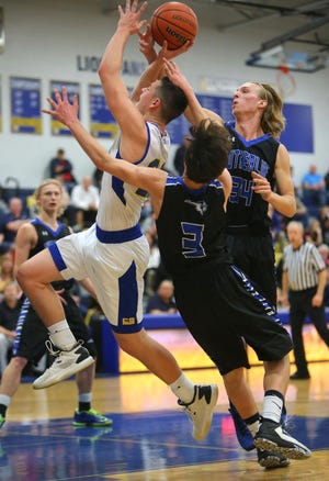 Cottage Grove's Blake Sentman is fouled as he drives to the hoop between a pair of Sutherlin defenders during their game Tuesday night. (Brian Davies/The Register-Guard)