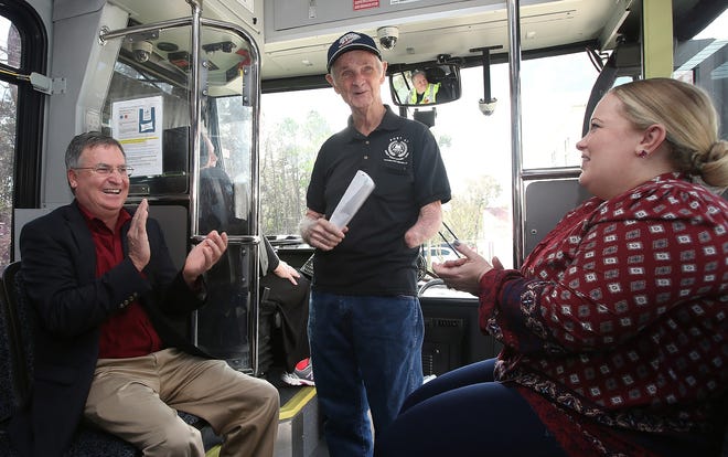 Panama City Commissioner Mike Nichols, left, and Angela Bradley, transit program administrator with the Bay County Transportation Planning Organization, clap for Navy veteran Don Sciefers after he received an annual pass for the Bay Town Trolley on Wednesday. [ANDREW WARDLOW/THE NEWS HERALD]