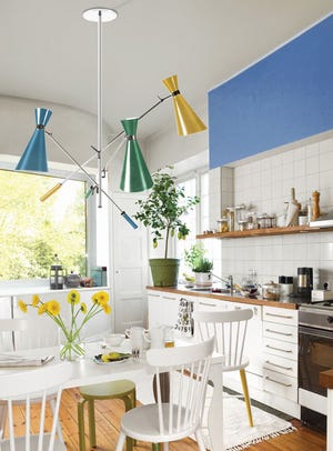 A contemporary light fixture paired with a bold blue wall paint over the counter can offset an all-white kitchen.