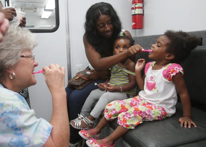 Takira Smitherman brushes her daughter Demirra Walker's teeth with her goddaughter Rah'Nicia Bright. Gulf Coast State College is offering free dental appointments for children ages 3-12 this week. NEWS HERALD FILE PHOTO