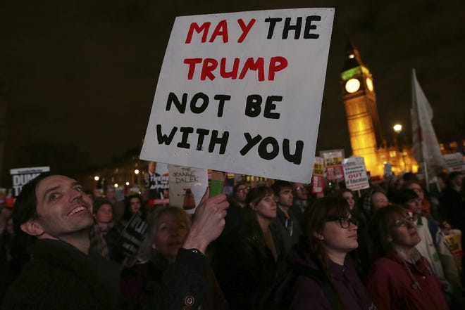 Demonstrators hold placards as they listen to speeches in London, Monday Feb. 20, 2017, during a rally in Parliament Square opposing U.S. President Donald Trump as Members of Parliament debate his planned state visit to the United Kingdom. (AP Photo/Tim Ireland)
