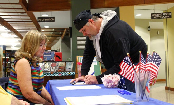 Karen Farris, treasurer of the Fort Smith League of Women Voters, aids Jerry Davis in updating his voter registration in September 2014 at the Fort Smith Public Library. The Arkansas Senate State Agencies and Governmental Affairs Committee on Tuesday endorsed the proposal requiring voters to show photo identification before they cast a ballot. TIMES RECORD FILE PHOTO