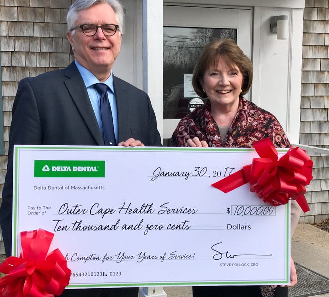 Dr. Rob Compton, retiring vice president of Delta Dental, presents a $10,000 donation to Patricia Nadle, CEO of Outer Cape Health Services. [Handout photo]