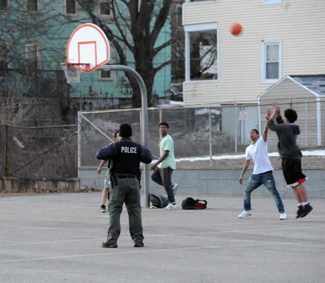 A Brockton police officer stands on the basketball court at the John L. O'Donnell Playground after gunshots were fired shortly before on it, Wednesday, Feb. 22, 2017.