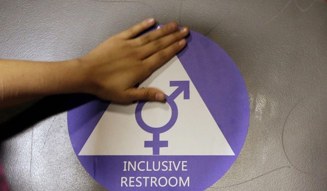 In this May 17, 2016 file photo, a new sticker is placed on the door at the ceremonial opening of a gender neutral bathroom at Nathan Hale High School in Seattle. A government official says the Trump administration will revoke guidelines that say transgender students should be allowed to use bathrooms and locker rooms matching their chosen gender identity. [ASSOCIATED PRESS FILE PHOTO/ELAINE THOMPSON]