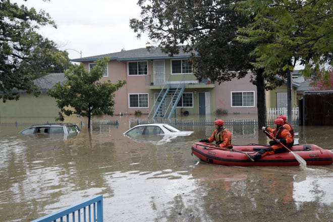 Rescuers travel by boat through a flooded neighborhood looking for stranded residents Tuesday, Feb. 21, 2017, in San Jose, Calif. Rescuers chest-deep in water steered boats carrying dozens of people, some with babies and pets, from a San Jose neighborhood inundated by water from an overflowing creek Tuesday. (AP Photo/Marcio Jose Sanchez)
