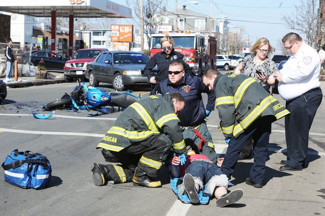 Firefighters and paramedics tend to an injured motorcyclist after a collision at Main and Market streets in Brockton, Thursday, Feb. 23, 2017.
