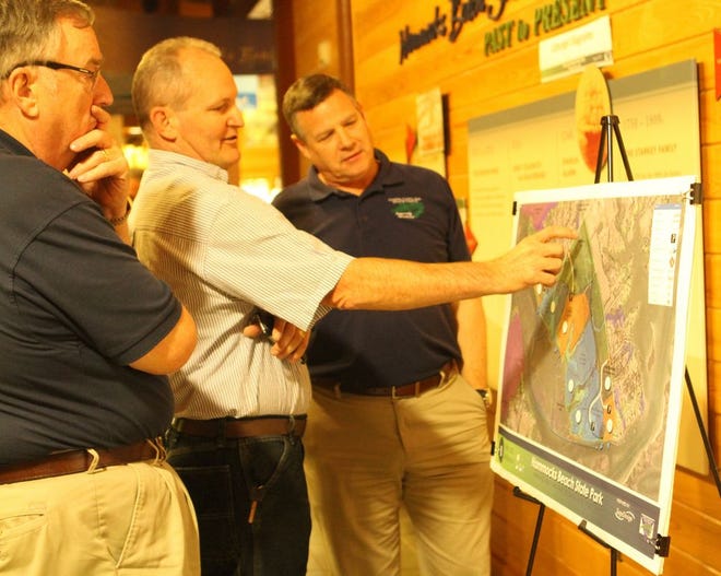 Swans Bluff subdivision residents Craig Brewer, left, and Rick Jehue, center, discuss with the Chief of Planning and Natural Resources Brian L. Strong features of one of two site plans on display inside the Visitor's Center of Hammocks Beach State Park Thursday evening. Photo by Mike McHugh / The Daily News