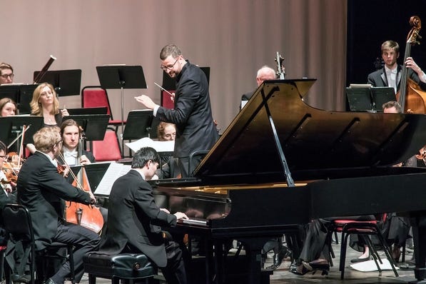 Conductor Dirk Meyer looks back at piano soloist Sheng Cai during Saturday's concert. [Photo By Richard Van Inwegen]