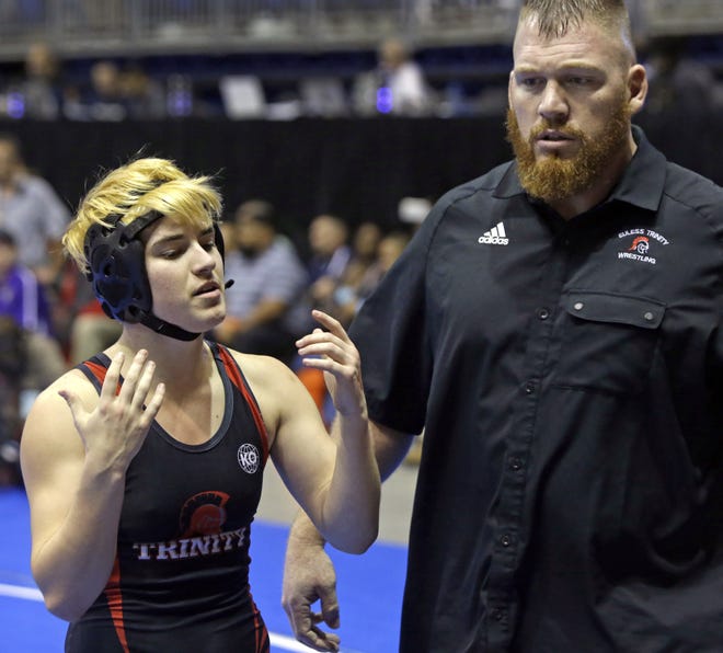 Mack Beggs, left, a transgender wrestler from Euless Trinity High School, stands with his coach Travis Clark during a quarterfinal match against Mya Engert, of Amarillo Tascosa, during the State Wrestling Tournament Friday in Cypress, Texas. [MELISSA PHILLIP / HOUSTON CHRONICLE via AP]