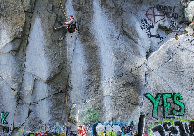 While much of Quincy's history has roots in the granite industry, towering granite walls and quarries have been filled with Big Dig fill, ledges which remain are populated by rock climbers and graffiti artists, Tuesday, April 8, 2014. Andrew Kravet of Boston climbs and descends ledges at the location of the former Swingles Quarry in West Quincy.