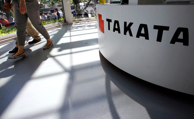 FILE - In this May 4, 2016, file photo, visitors walk by a Takata Corp. desk at an automaker’s showroom in Tokyo. Japanese auto parts maker Takata Corp. is expected to plead guilty in U.S. District Court in Detroit on Monday, Feb. 27, 2017, to a criminal charge and agree to a $1 billion penalty for concealing a deadly air bag inflator problem. (AP Photo/Shizuo Kambayashi, File)