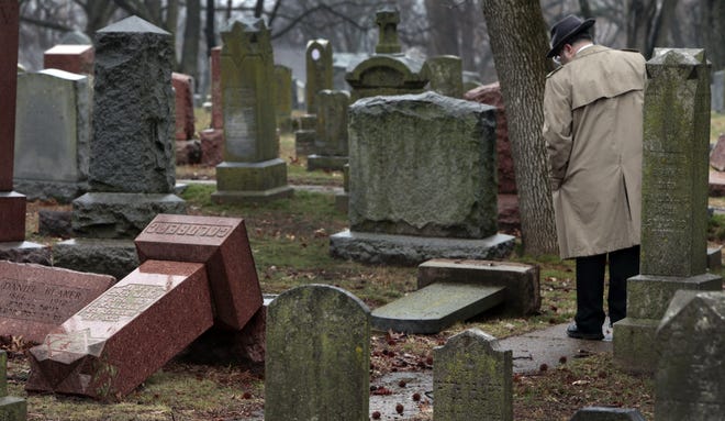 People walk through toppled graves at Chesed Shel Emeth Cemetery in University City, Mo., on Tuesday, Feb. 21, 2017. Authorities in Missouri are investigating after dozens of headstones were tipped over at the Jewish cemetery near St. Louis. (Robert Cohen /St. Louis Post-Dispatch via AP)