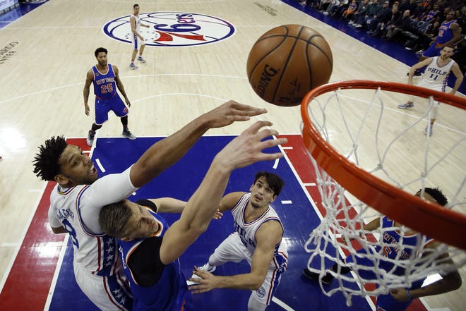 The 76ers' Jahlil Okafor, left, leaps for a rebound over the Knicks' Kristaps Porzingis, center, as Dario Saric looks on during the first half of Friday night's game in Philadelphia. [The Associated Press]