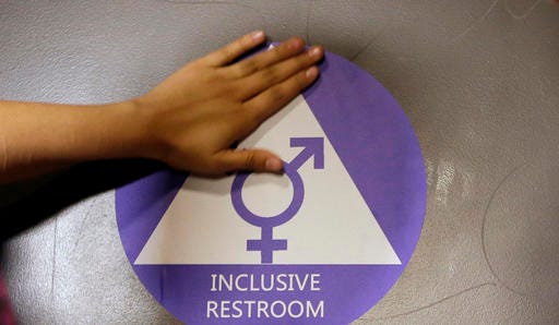 A new sticker is placed on the door at the ceremonial opening of a gender neutral bathroom at Nathan Hale High School in Seattle in May. (AP Photo/Elaine Thompson, File)